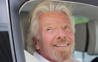 Richard Branson smiling smugly out of a car window